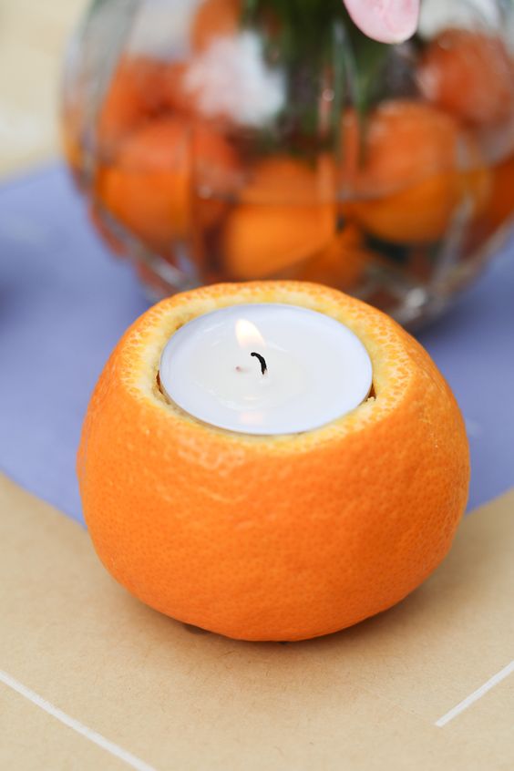 A clementine holds a tea light.