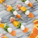 Citrus caprese skewers on a marble counter.
